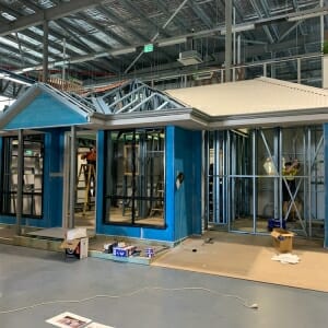 Partially constructed house display with exposed frame, open garage and roof section