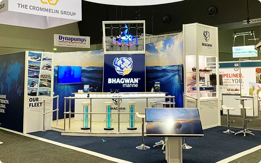 Exhibition booth for Bhagwan Marine featuring a blue and white color scheme, central logo, digital screens, and marine-themed decor, conveying a professional and nautical vibe.