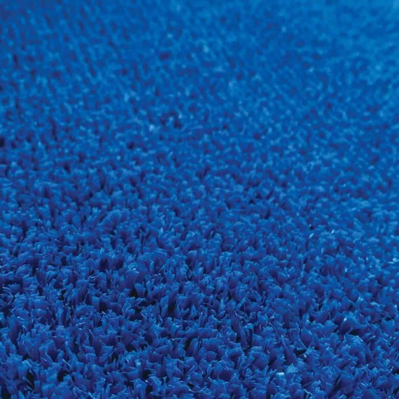 Close-up of densely packed blue bristles, resembling artificial turf or carpet fibers. The texture is vibrant, creating an intense, uniform blue surface