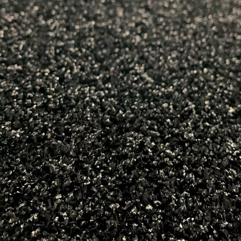 Close-up of a textured black surface with small, shiny granules reflecting light. The image conveys a sense of intricacy and subtle sparkle