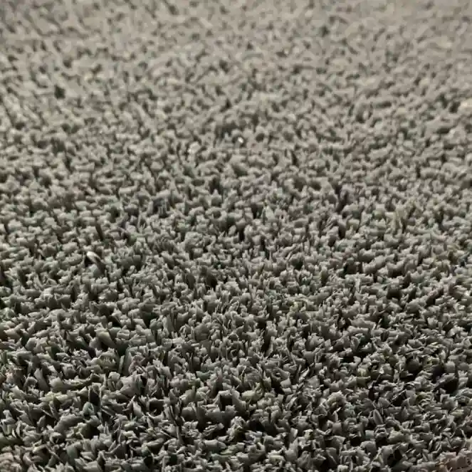 Close-up of a gray faux grass texture, showing dense, short strands densely packed together. The surface appears uniform and slightly rough