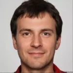 A smiling man with short dark hair against a plain background. He is wearing a red collared shirt. The tone is positive and welcoming.