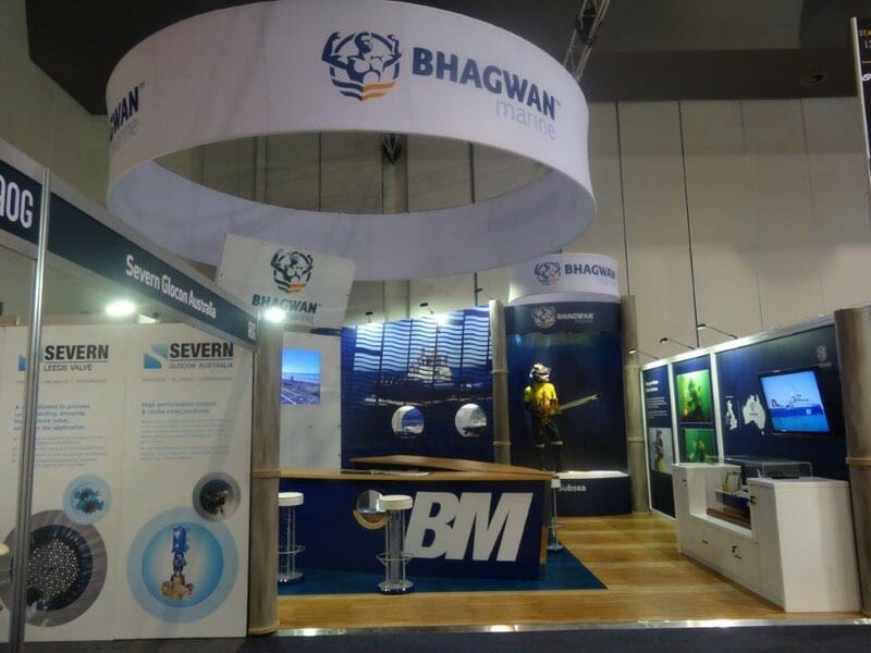 Trade show booth with "Bhagwan Marine" signage featuring maritime images, displays, and a mannequin in diving gear. The setting is modern and professional.