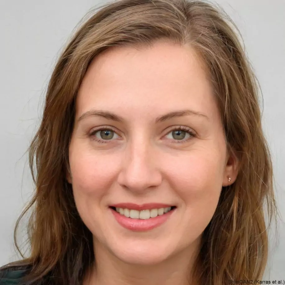 A woman with light brown hair and green eyes is smiling at the camera. She appears content and relaxed, set against a plain grey background
