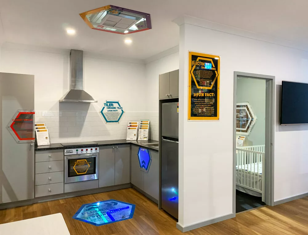 Modern kitchen with metallic appliances, hexagonal colorful lights on walls and floor, and a crib in an adjacent room. Sleek and futuristic design.