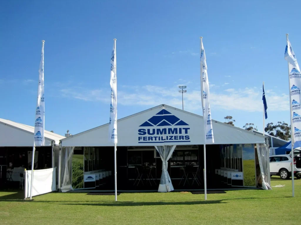 Large white tent designed by Barrett Exhibition Group Perth with "Summit Fertilizers" logo, set on green grass with flags and clear blue sky.