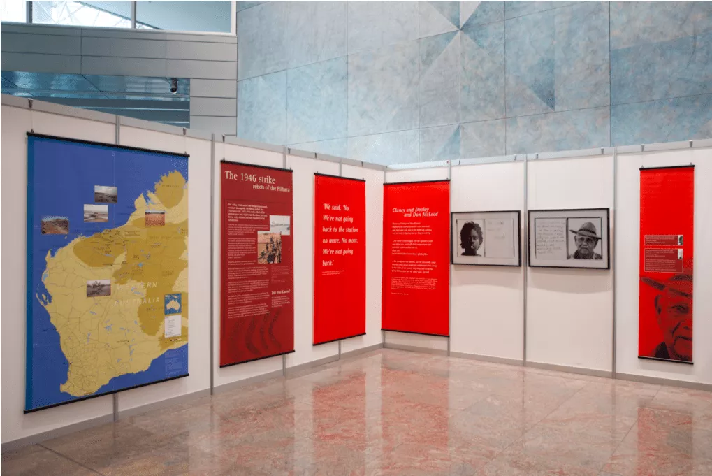 Exhibit with large colorful panels, highlighting historical text and images. Blue map, red text display, and monochrome portraits