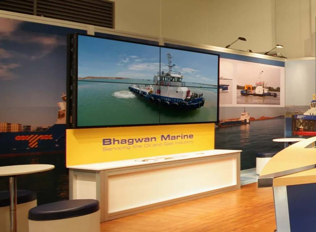Exhibition booth with "Bhagwan Marine" sign, showcasing a large screen of a vessel at sea