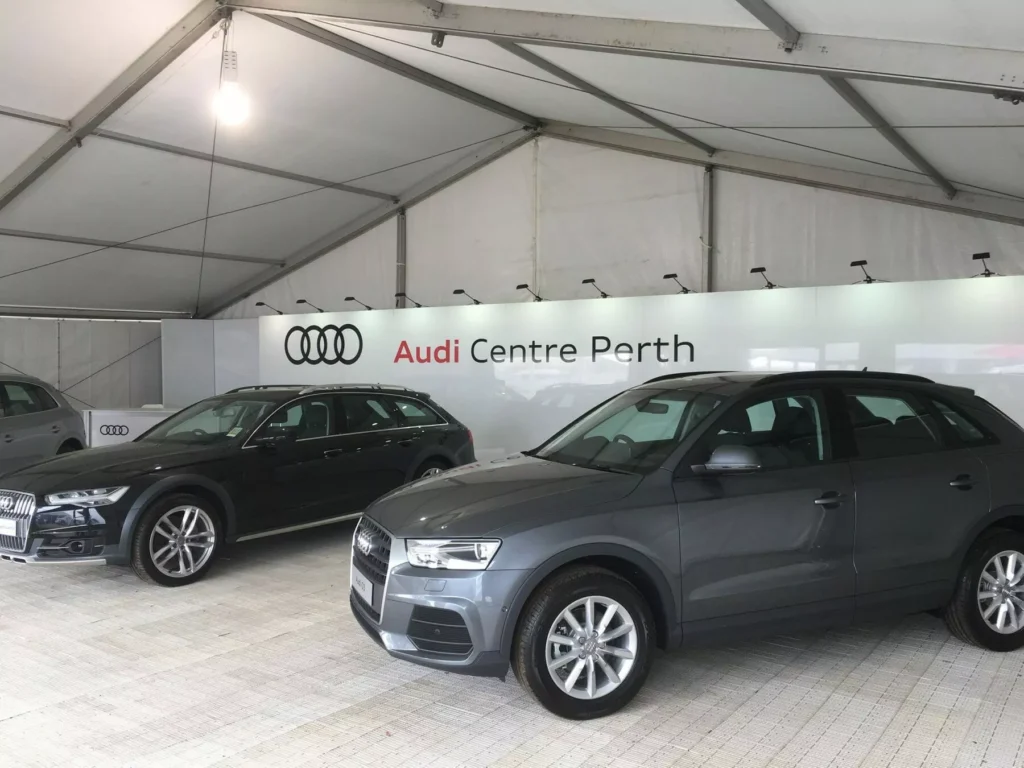 Two gray SUVs displayed under a tent with "Audi Centre Perth" signage in the background, creating a sleek and modern atmosphere