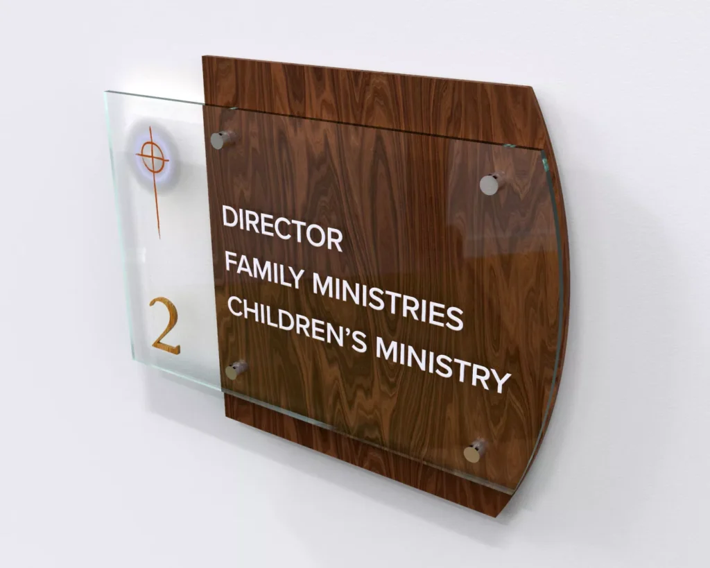 Wall-mounted sign with wood and glass design, reading "Director Family Ministries Children's Ministry." Features an orange cross and the number 2