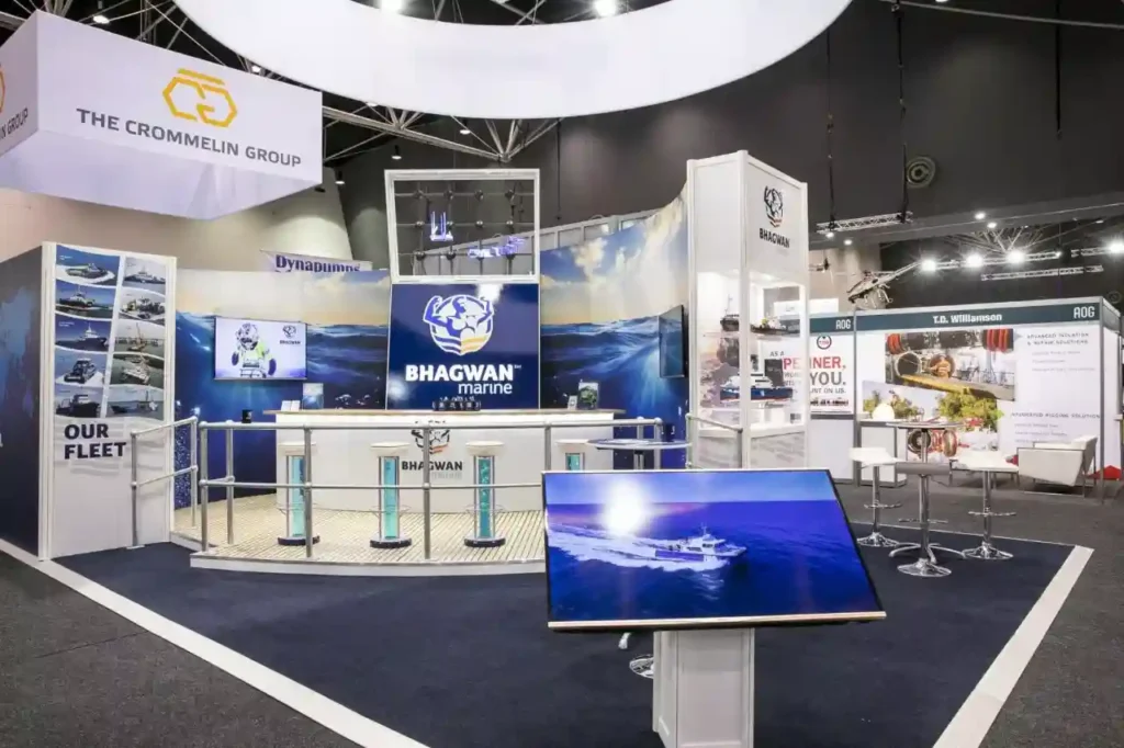 Exhibition booth featuring "Bhagwan Marine" branding with nautical imagery, a central counter with brochures, and a screen displaying a marine vessel.