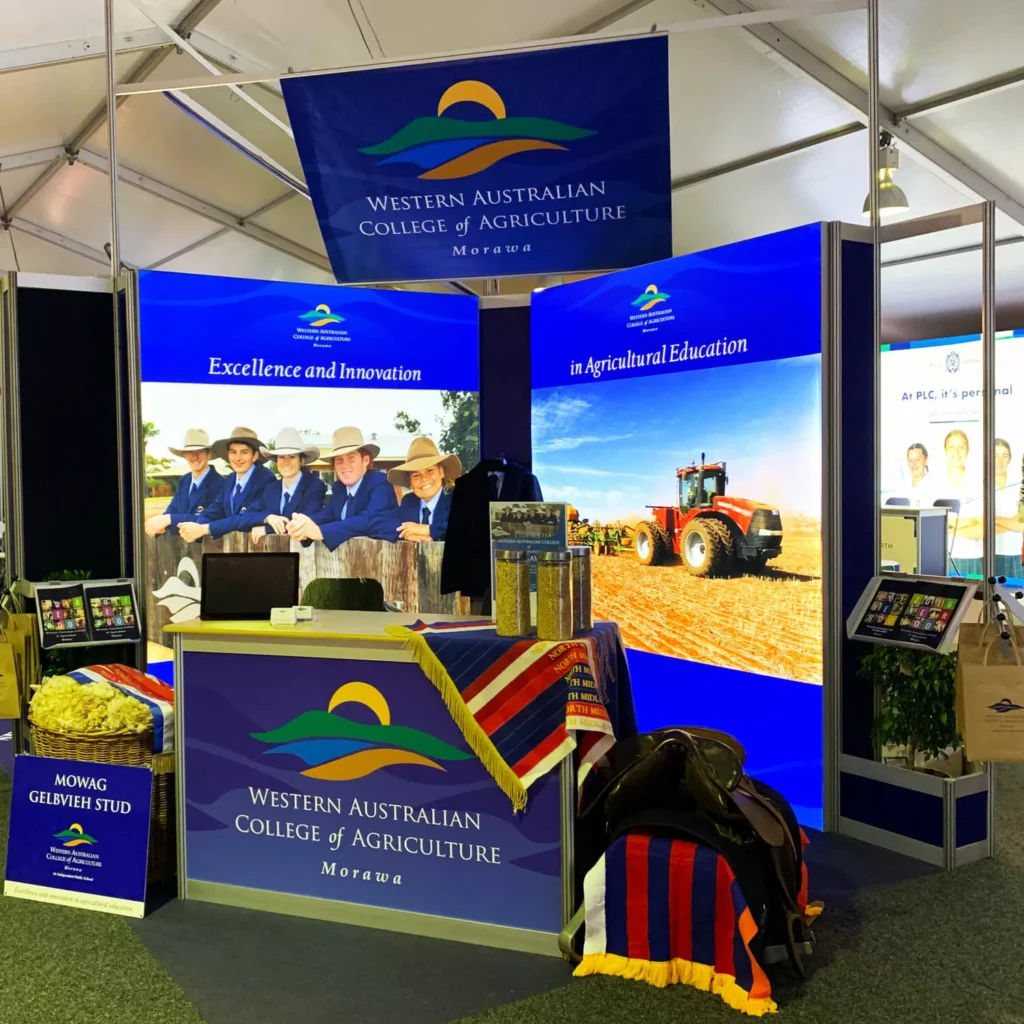 Exhibition booth for the Western Australian College of Agriculture, featuring banners with students, a tractor, and educational displays, emphasizing innovation.