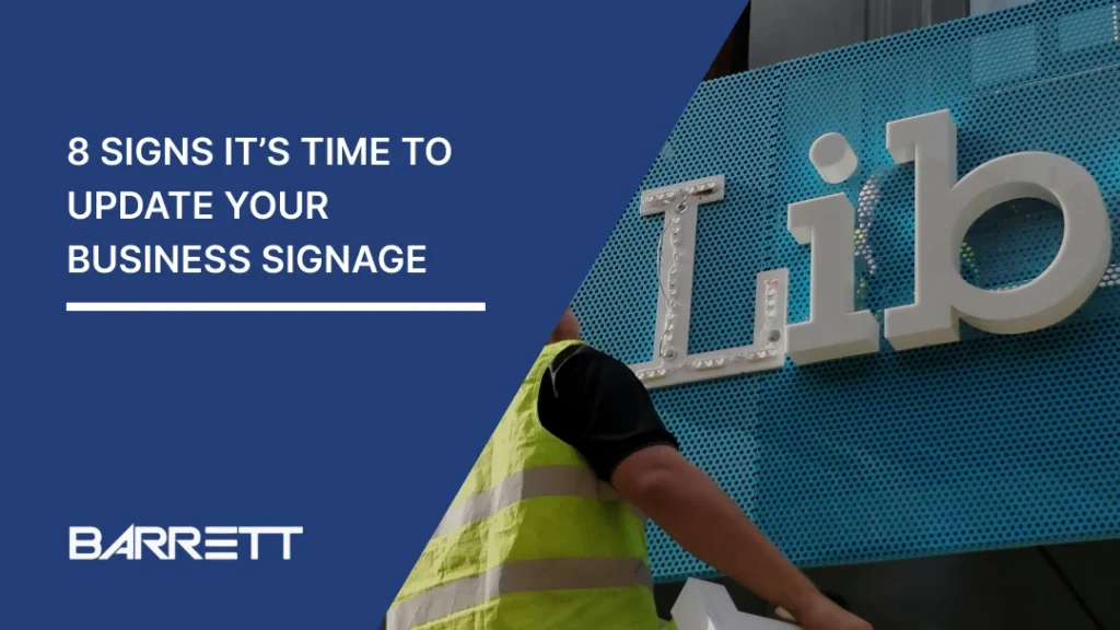 A Barrett Exhibition Group blog banner titled “8 Signs It’s Time to Update Your Business Signage,” featuring a worker wearing a high-visibility yellow vest installing large three-dimensional letters on a blue perforated exterior building facade. The design includes a navy blue diagonal overlay, white headline text and the Barrett logo.